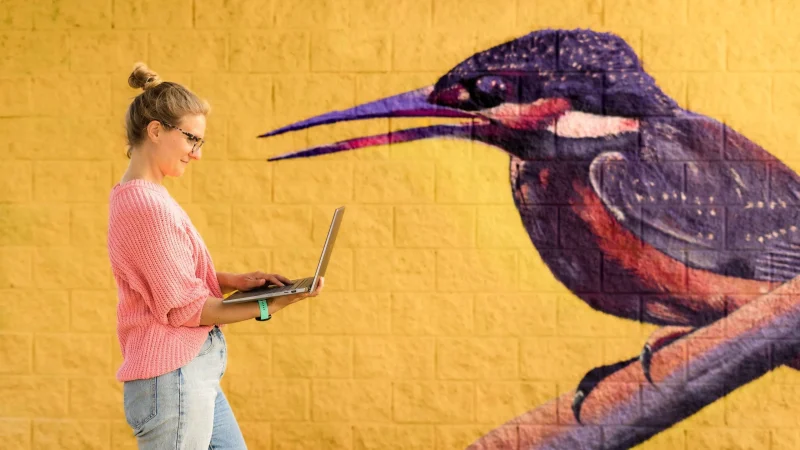 Jolien met laptop voor gele achtergrond met vogel